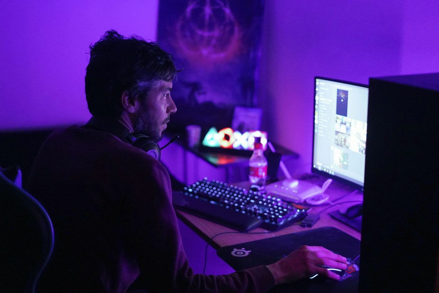 Een man met een headset achter een computer in paars licht